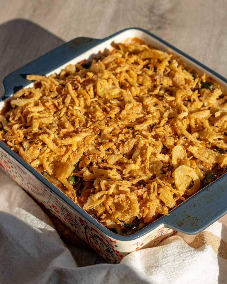 a baking pan full of vegan green bean casserole, topped with crunchy fried onions
