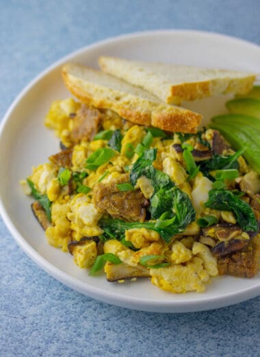 soft tofu scramble with a piece of toast and sliced avocado on a plate