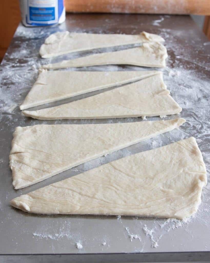 vegan croissant dough rolled out and cut into triangles to shape