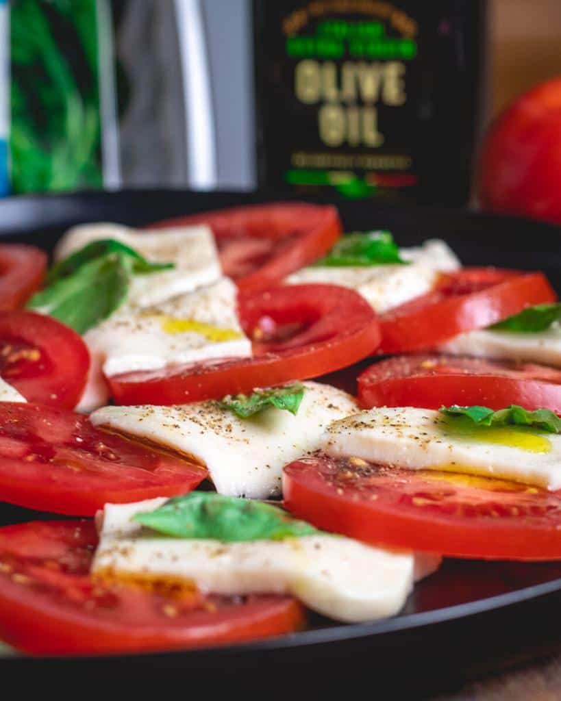 closeup shot of caprese salad with sliced tomatoes, mozzarella and basil