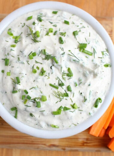 overhead shot of vegan ranch garnished with chives and dill and served with a side of carrots and celery
