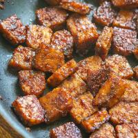closeup of tempeh in a pan coated with the bacon marinade