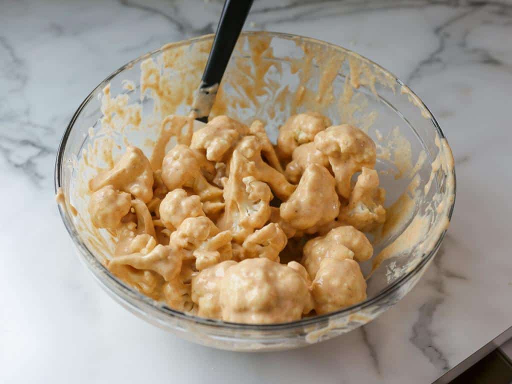 mixing bowl of cauliflower florets coated in batter