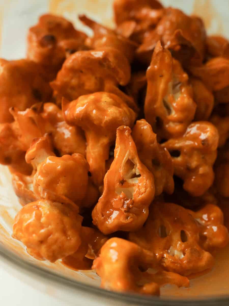 mixing bowl of battered and baked buffalo cauliflower just tossed in buffalo sauce