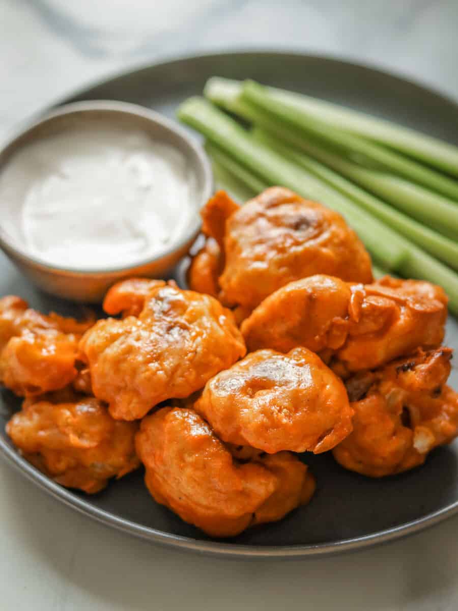 buffalo cauliflower wings on a plate with ranch dressing and sliced celery
