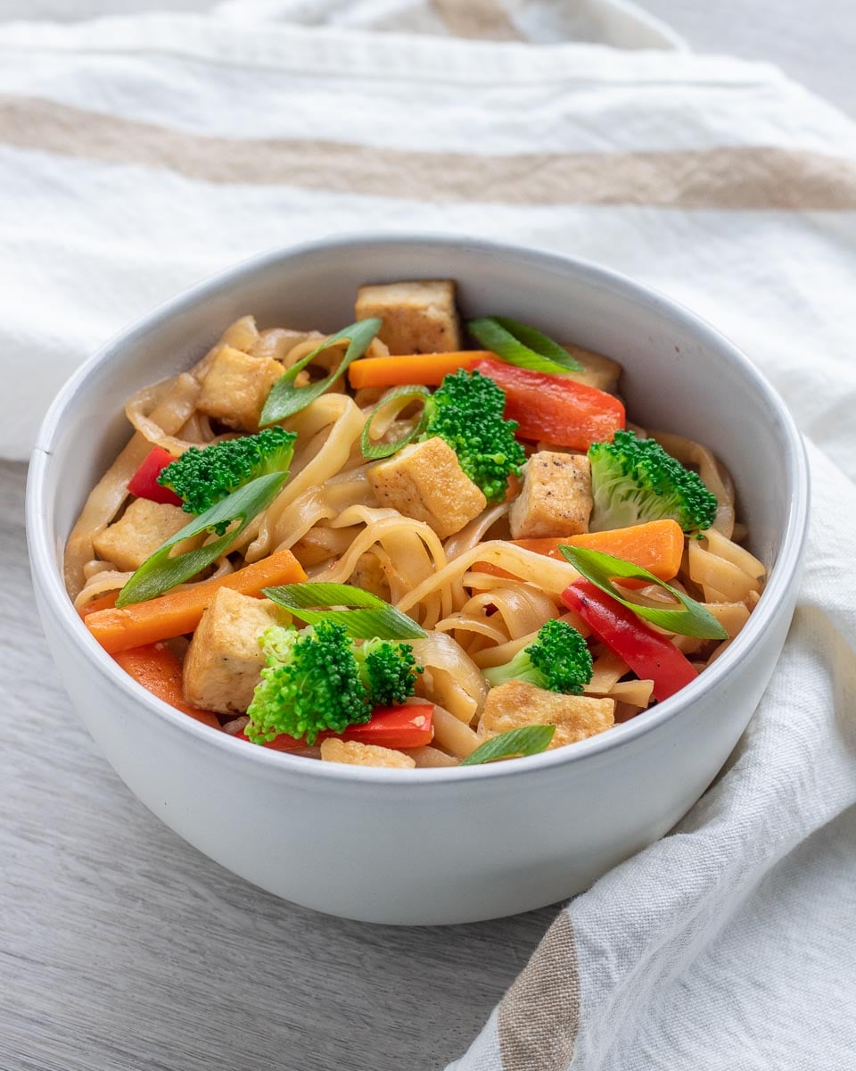 bowl of vegan stir fry noodles garnished with green onions