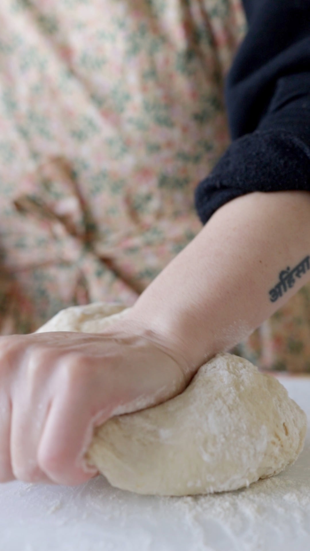 a ball of dough being kneaded by hand on a plastic cutting board