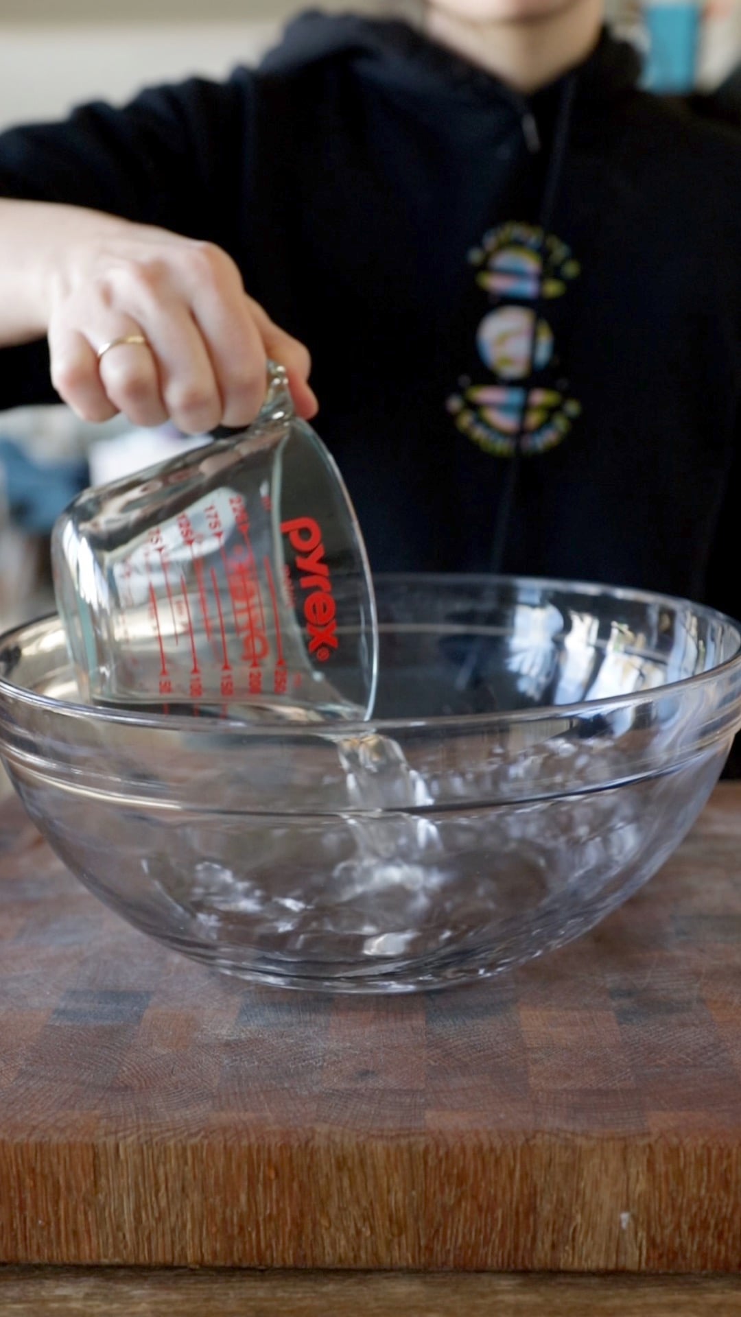 water being poured out of a Pyrex measuring cup into a large glass mixing bowl