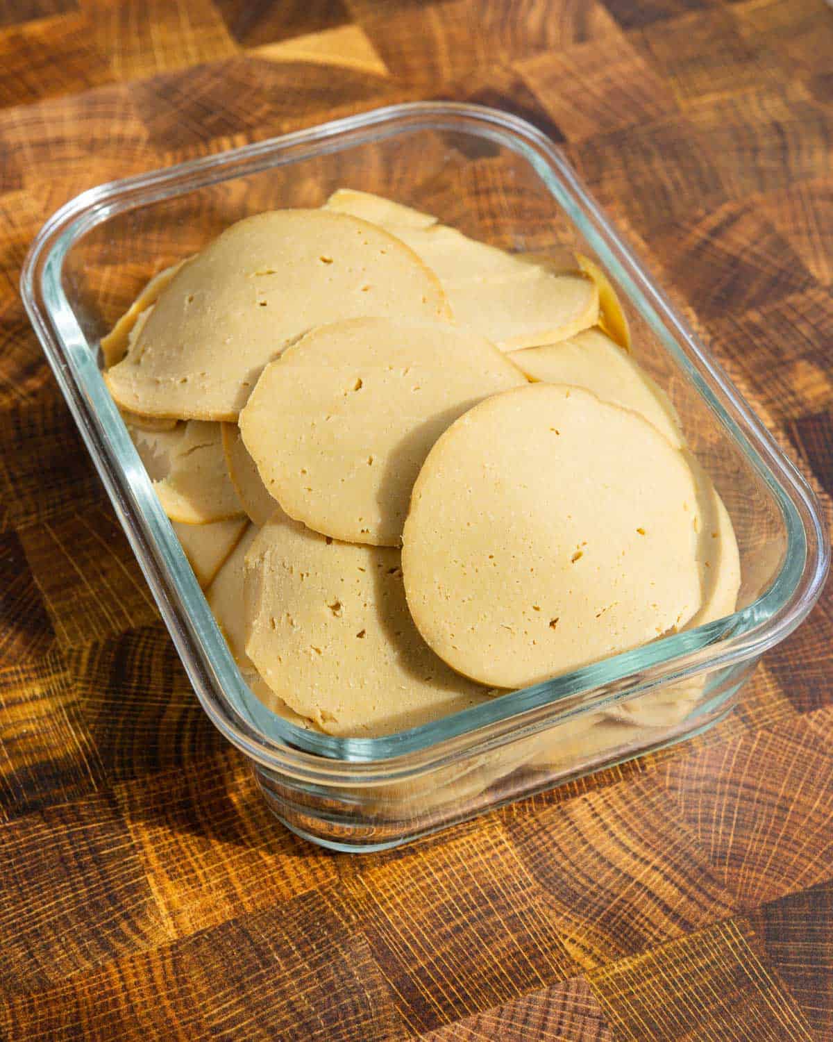 slices of vegan deli meat in a glass food storage container