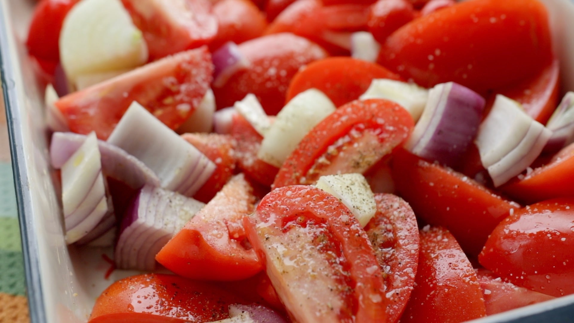 tomatoes, red onion, and garlic tossed with olive oil in a baking dish before roasting