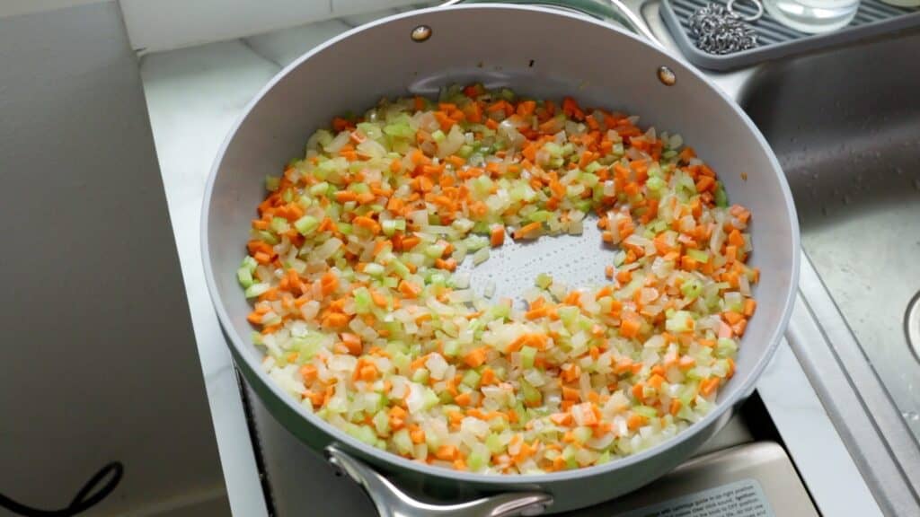 finely diced carrot, onion, and celery sautéing in olive oil and vegan butter in a large pan