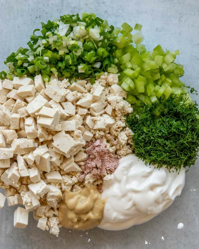 A closeup shot of ingredients for tofu egg salad in a mixing bowl.