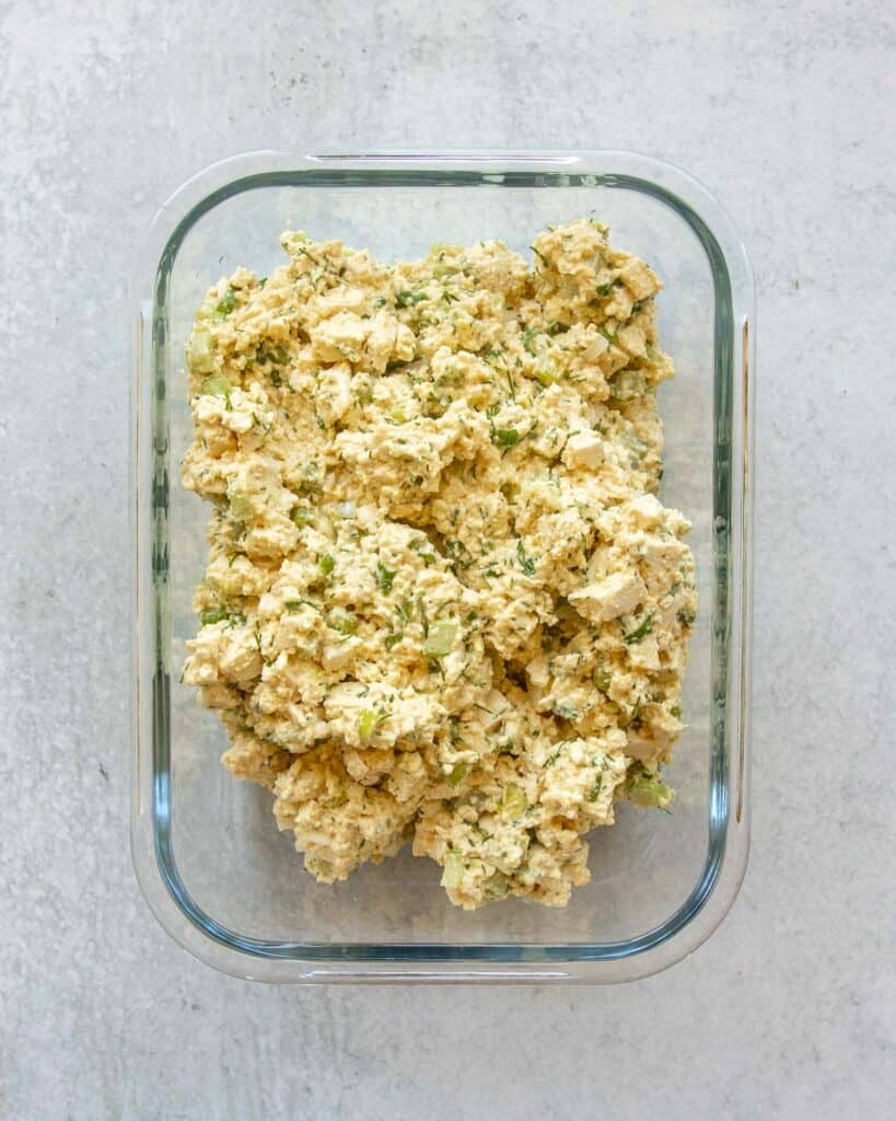 An overhead shot of tofu egg salad in a storage container, ready to be refrigerated.