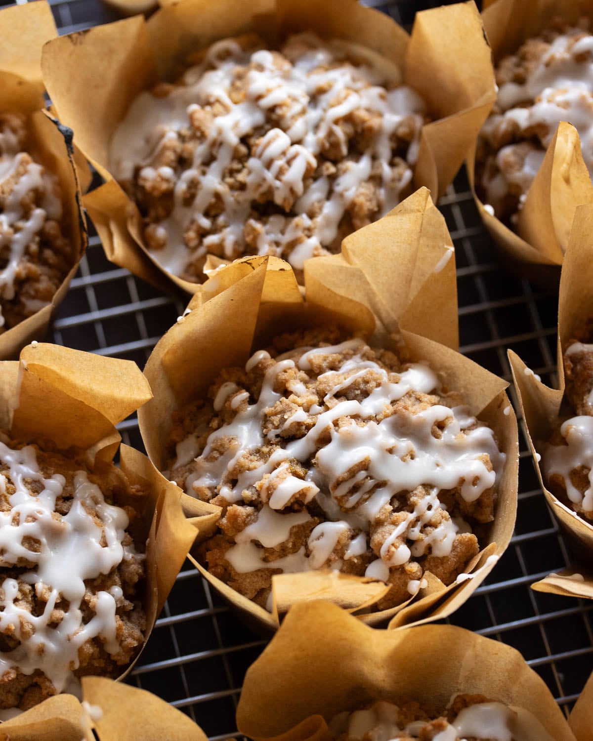 a close up shot of vegan pumpkin streusel muffins, drizzled with white icing