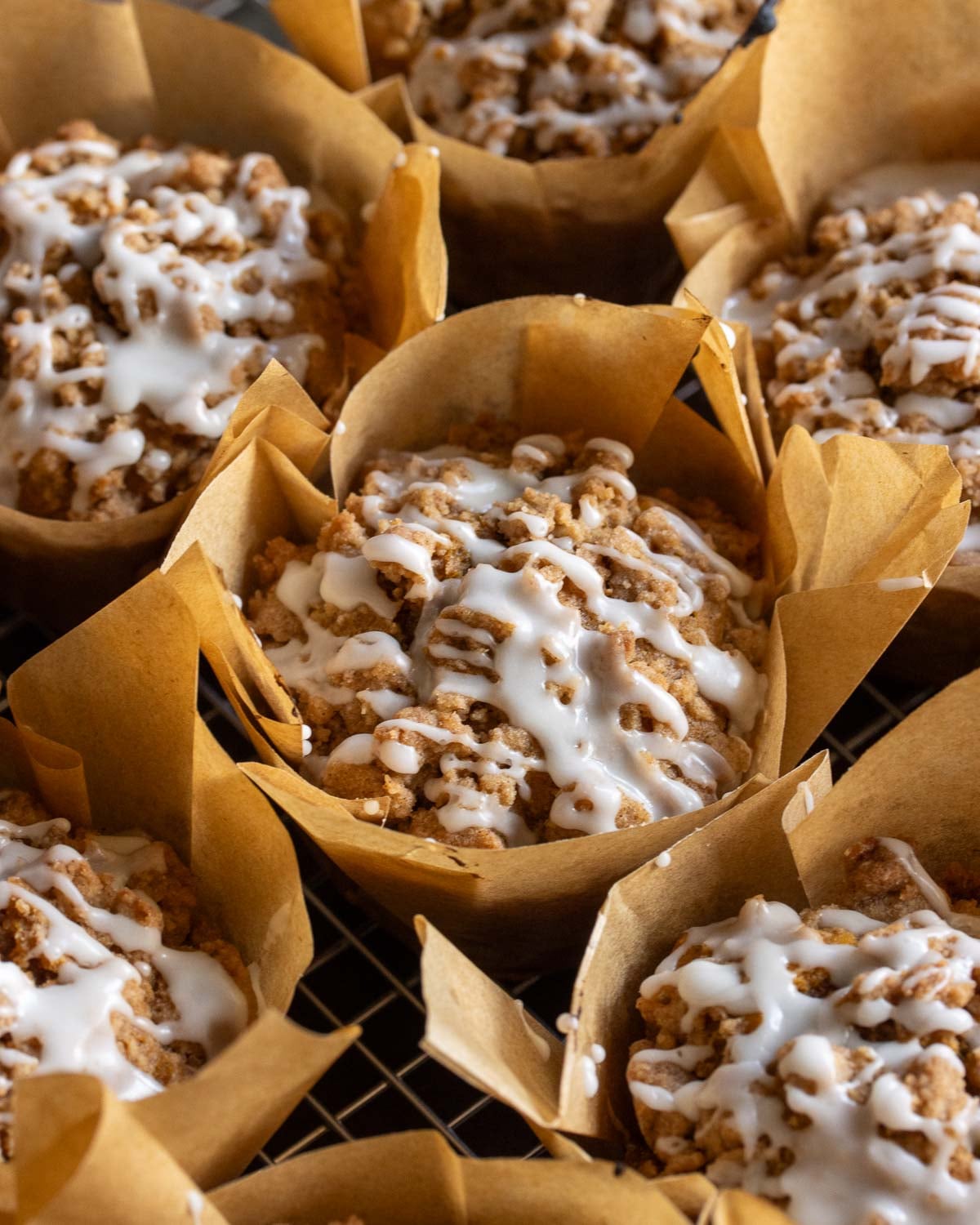 a close up shot of vegan pumpkin streusel muffins, drizzled with white icing