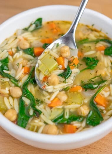 a bowl of lemon chickpea orzo soup, with a spoonful of soup