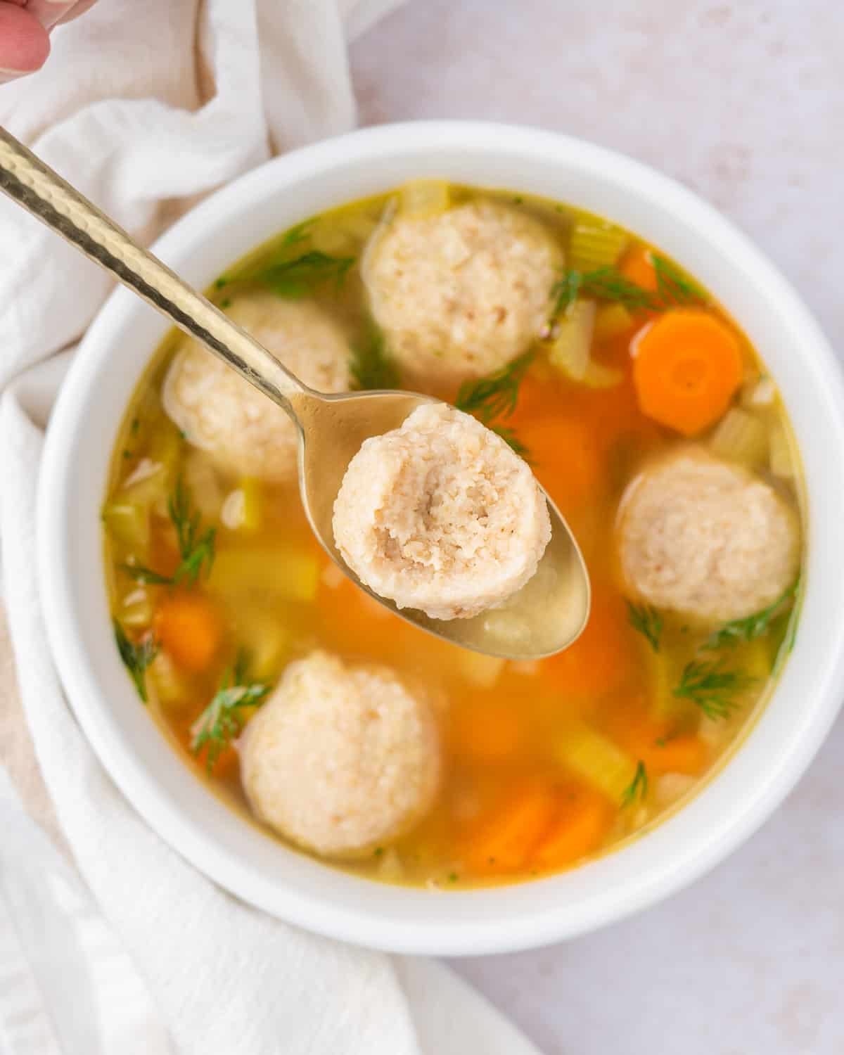overhead shot of the cross-section of a vegan matzo ball, with a bowl of soup in the background