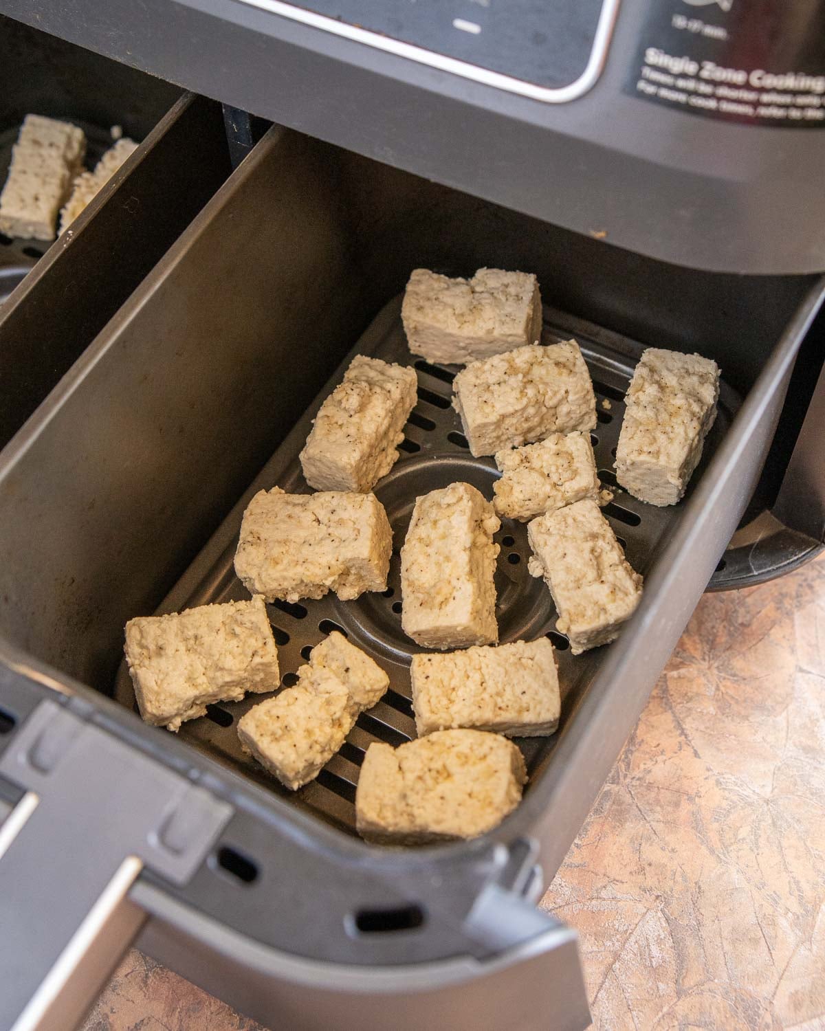 tofu nuggets cooking in an air fryer basket