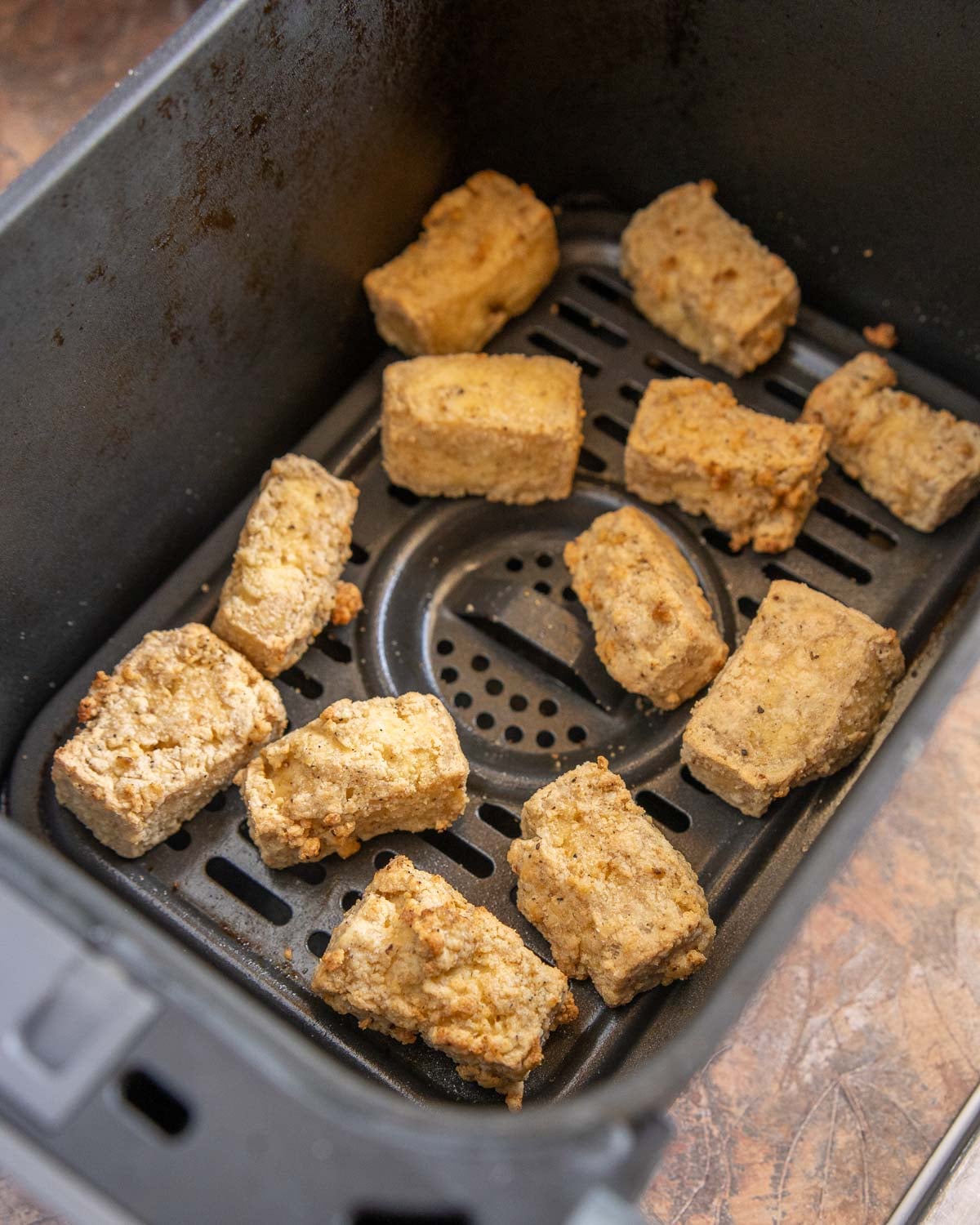 closeup of cooked tofu inside air fryer basket