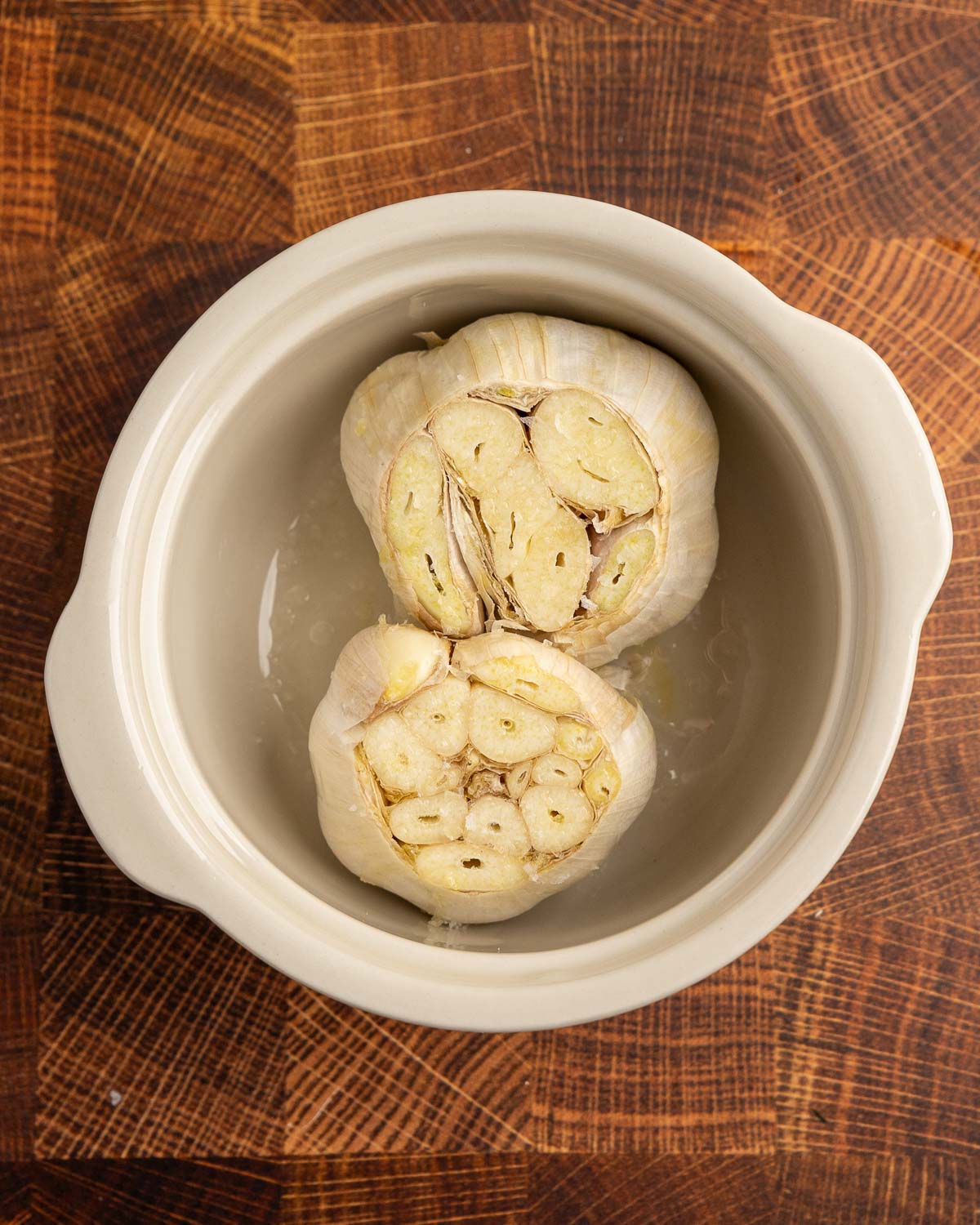 2 heads of raw garlic with the tops sliced off in a ramekin and topped with olive oil and salt