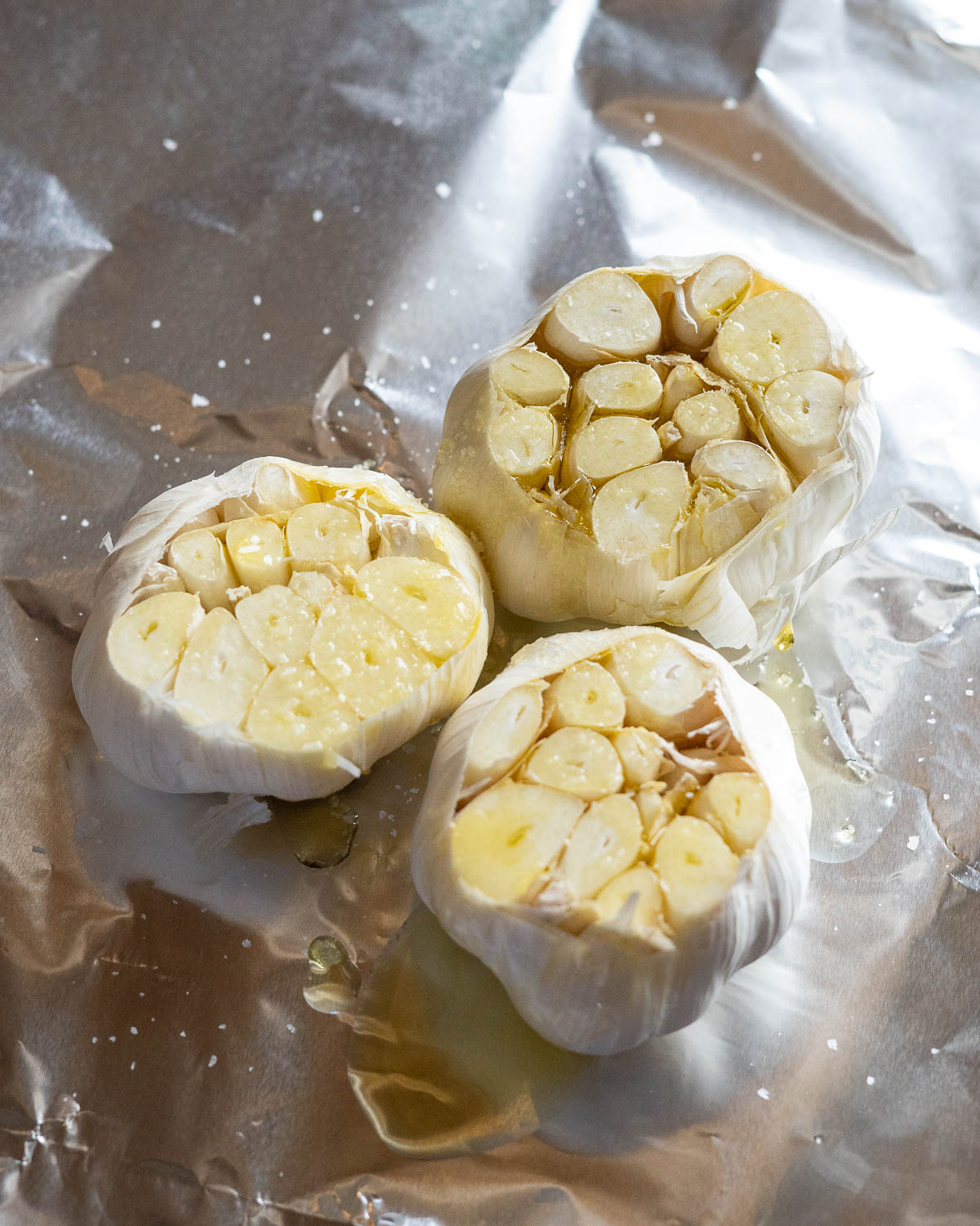 3 heads of raw garlic with the tops sliced off in tinfoil and topped with olive oil and salt