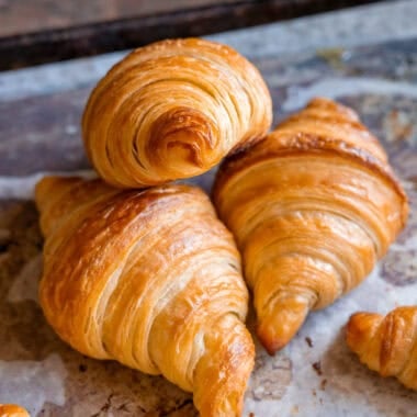 three freshly baked vegan croissants on a parchment-lined baking tray