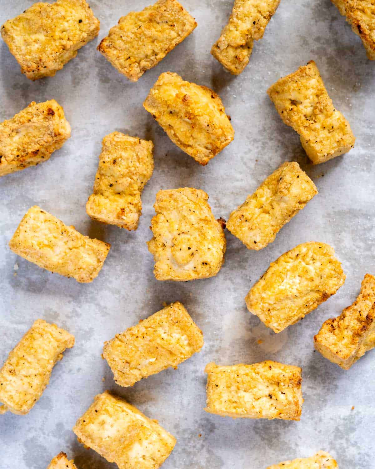 pieces of crispy baked tofu on a lined baking tray