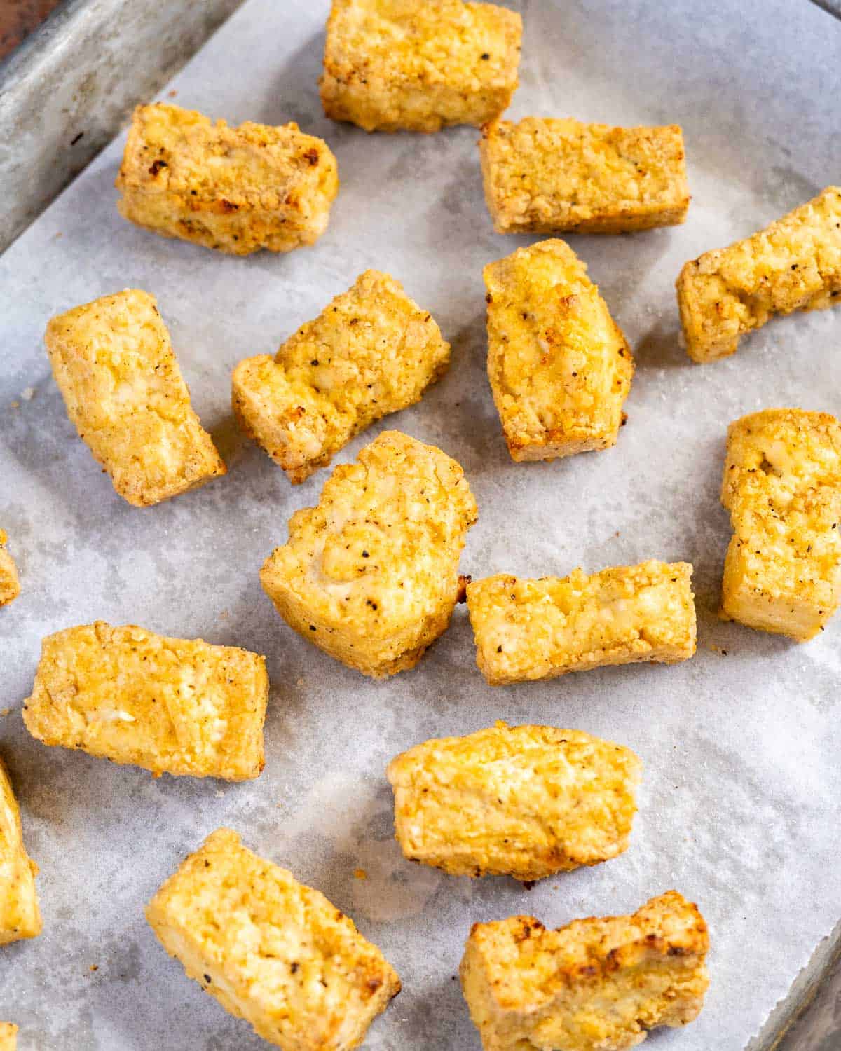 pieces of crispy baked tofu on a lined baking tray