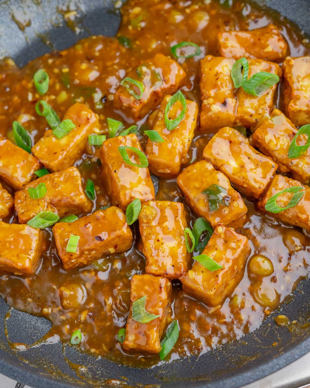 Closeup of saucy orange tofu in pan.