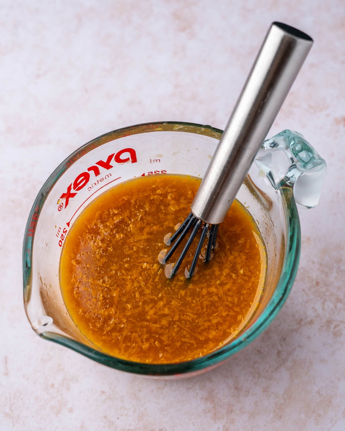 Orange sauce ingredients whisked together in a measuring cup.