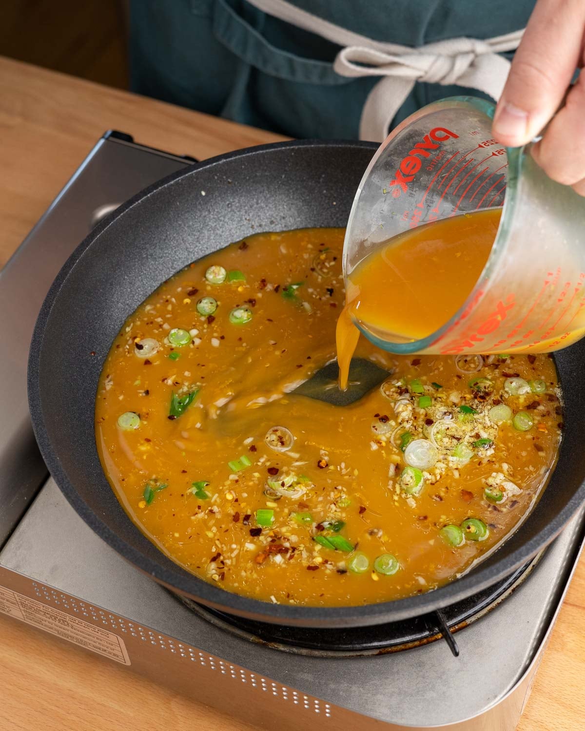 Adding orange juice to aromatics for orange sauce.