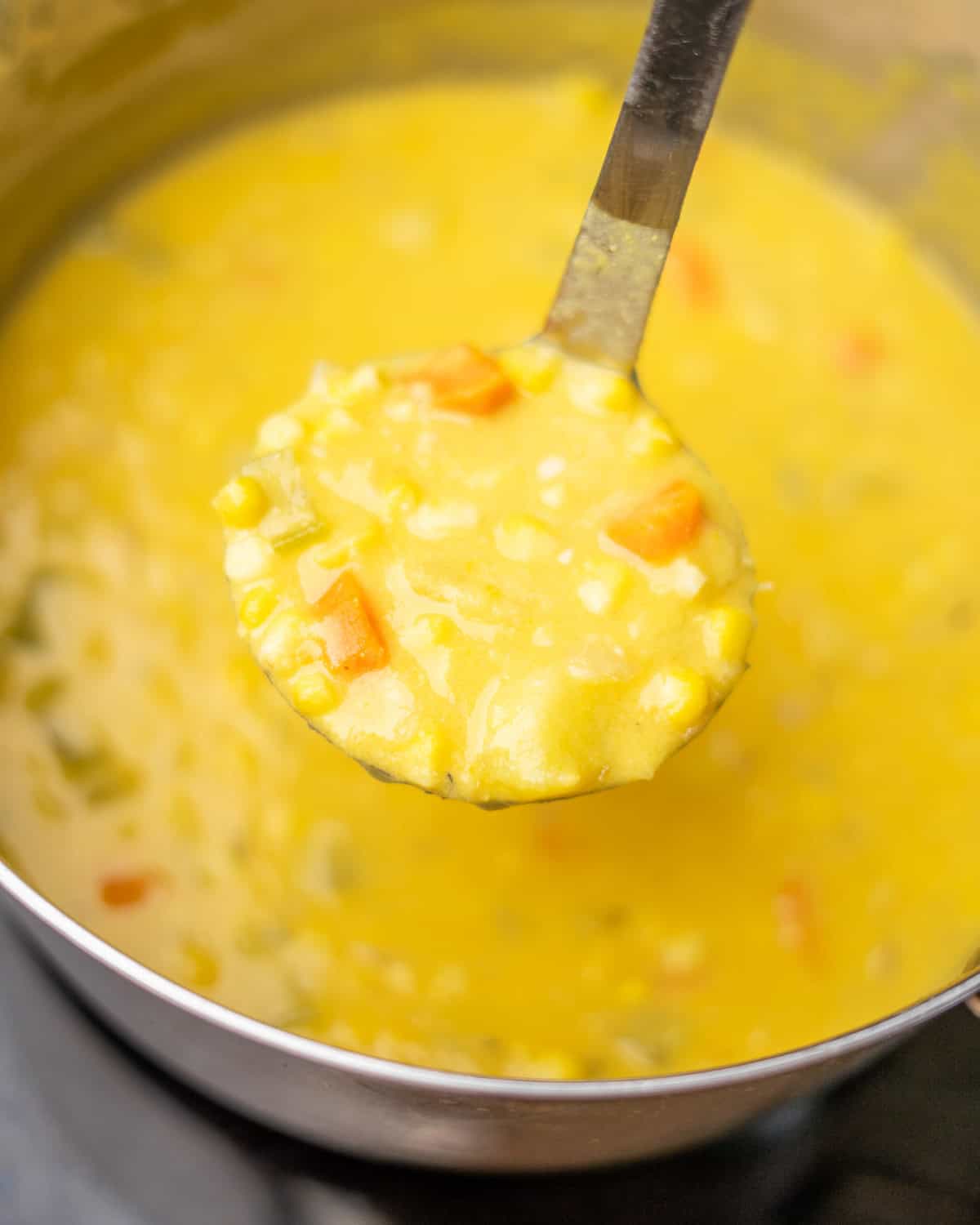 Closeup of ladle of corn chowder.