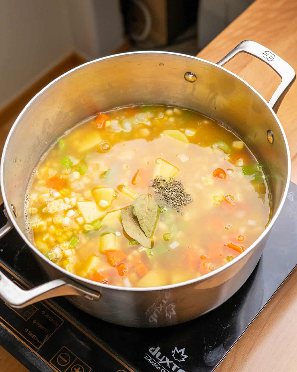 Broth and herbs added to soup pot.