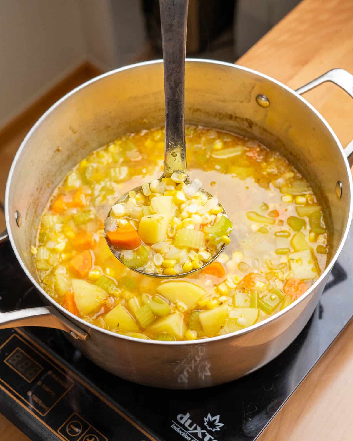 Ladle of vegan corn chowder before blending.