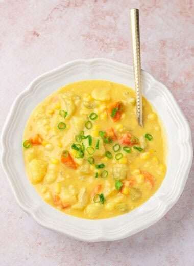 a bowl of vegan potato corn chowder, topped with chopped scallions
