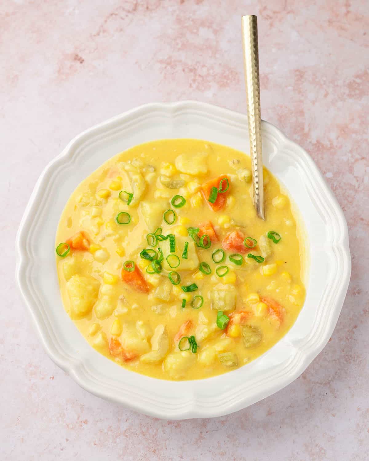 a bowl of vegan potato corn chowder, topped with chopped scallions