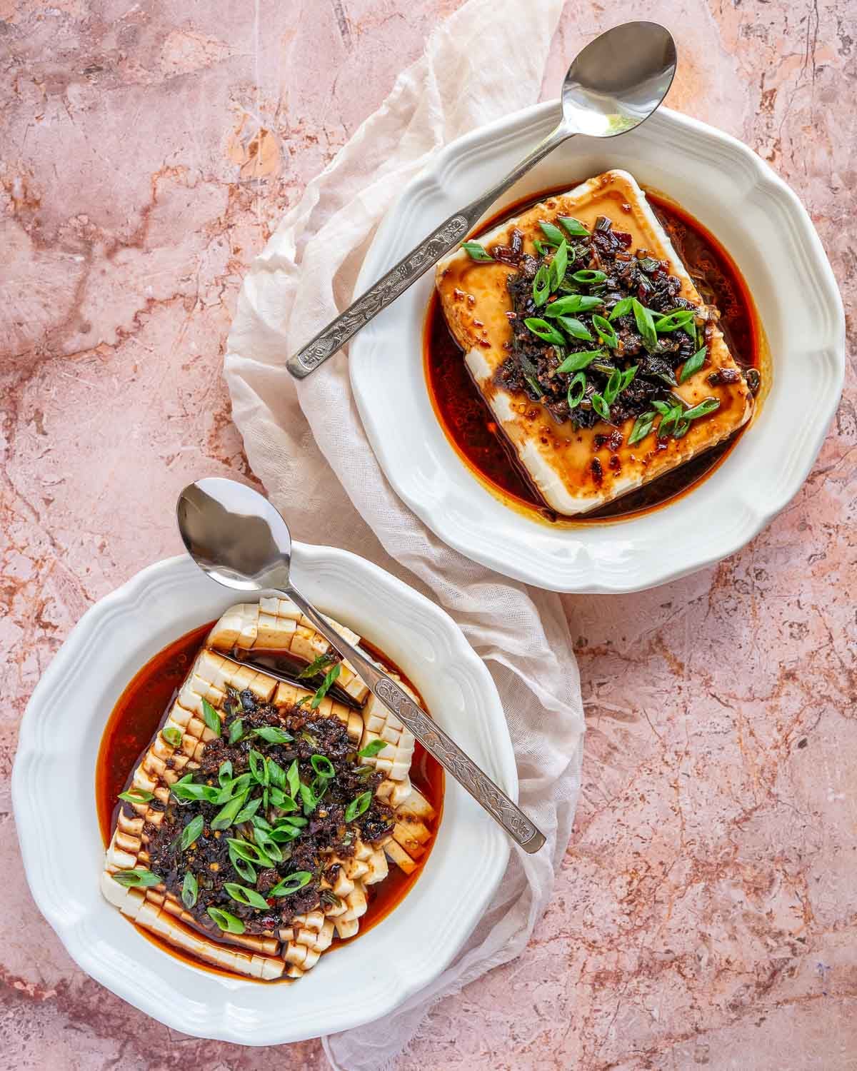 Overhead shot of two bowls of chili garlic tofu with different presentations