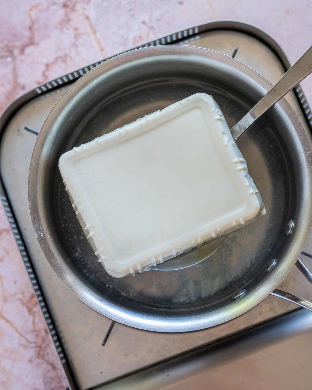 lifting poached silken tofu out of pot