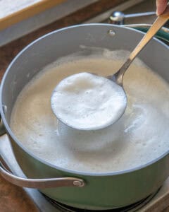 Skimming off the foam from the pot of soymilk