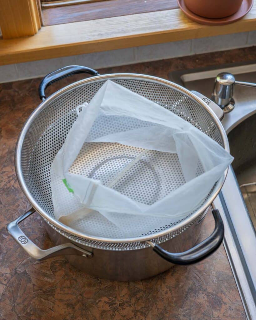 Colander placed over pot lined with nut milk bag