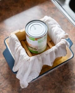 Tofu in mold weighed down with a can to press out extra liquid