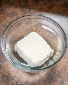 Homemade tofu placed in bowl of cold water