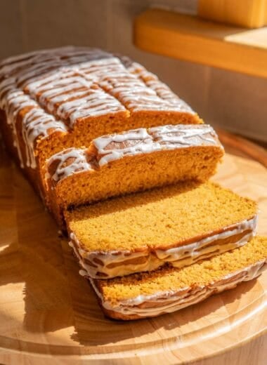 loaf of vegan pumpkin bread, with three slices cut off of it
