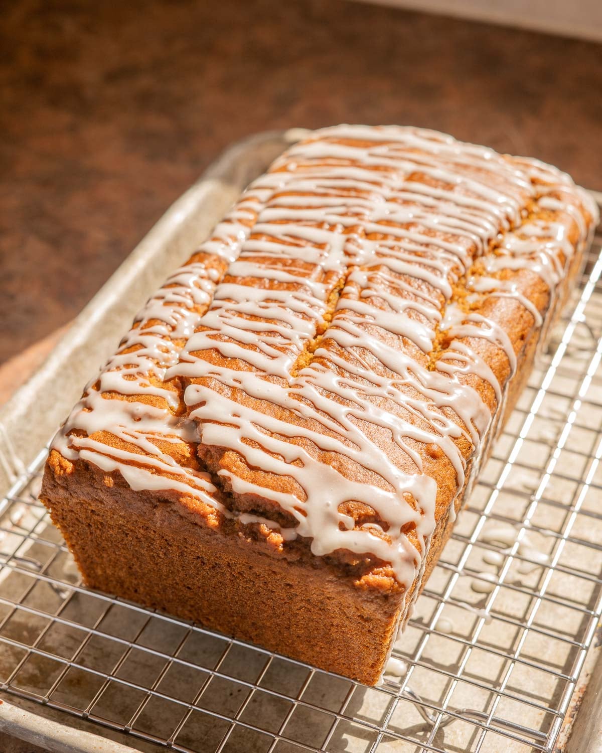 loaf of vegan pumpkin bread, drizzled with a glaze