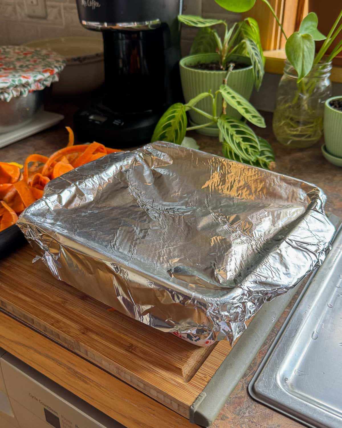 baking dish with carrots wrapped in foil to trap steam