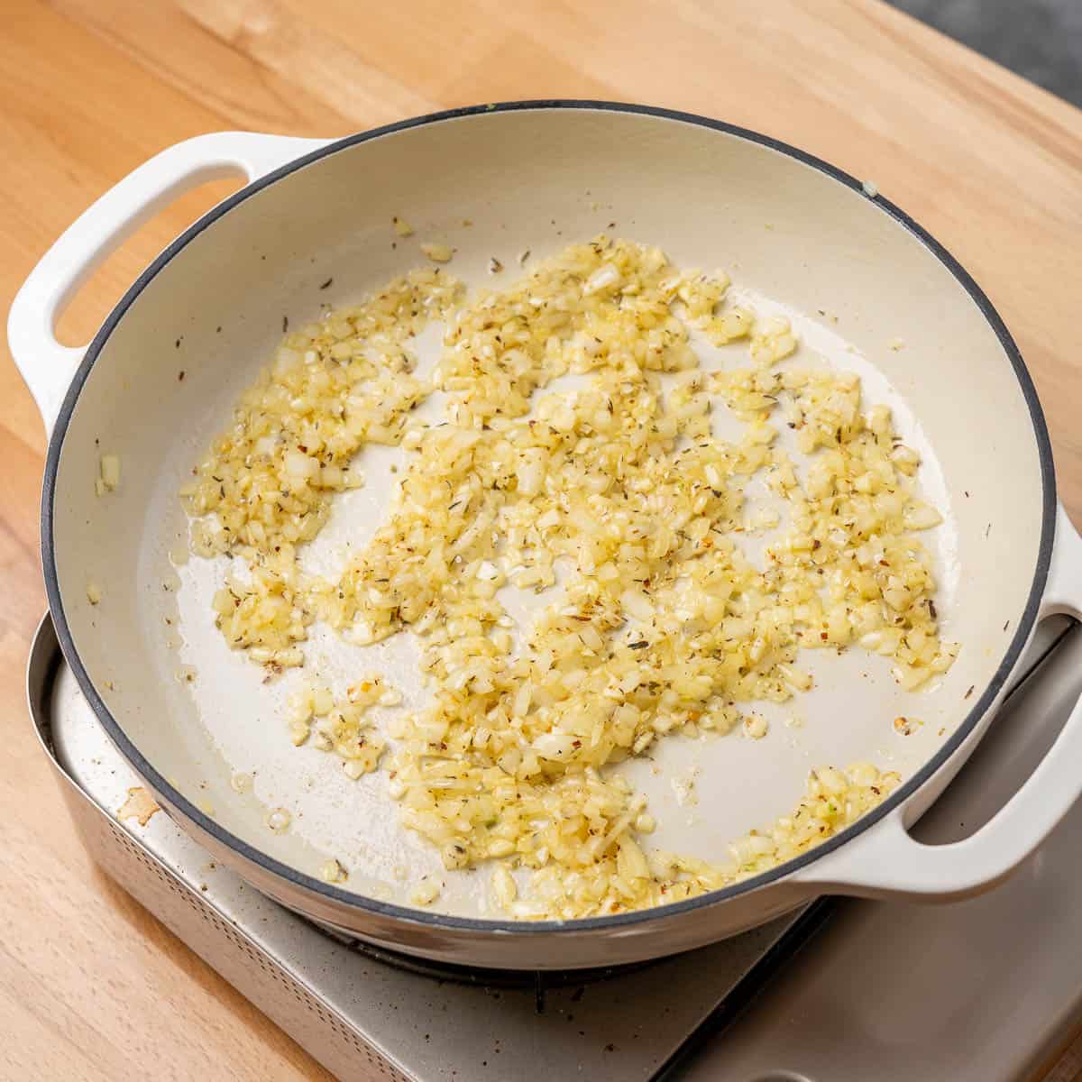 diced onion and red pepper flakes sautéing in a braiser pan