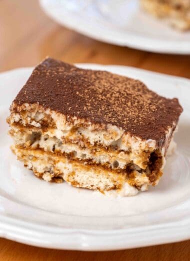 a piece of vegan tiramisu on a plate, showing all of the layers
