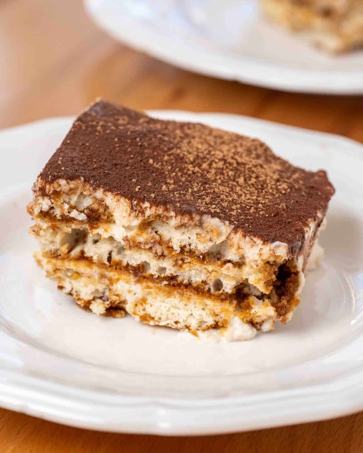 a piece of vegan tiramisu on a plate, showing all of the layers