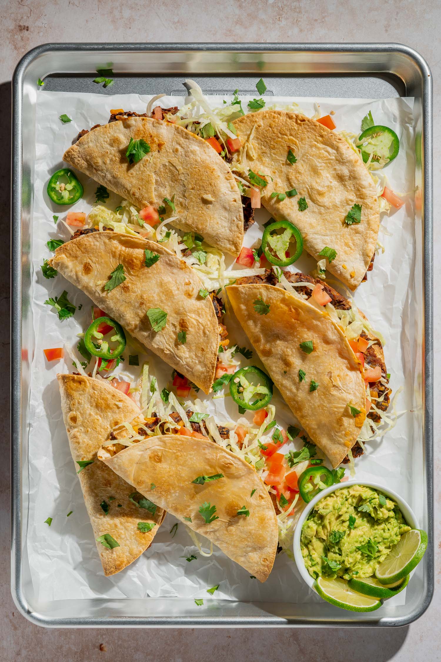 tray of baked tacos with toppings