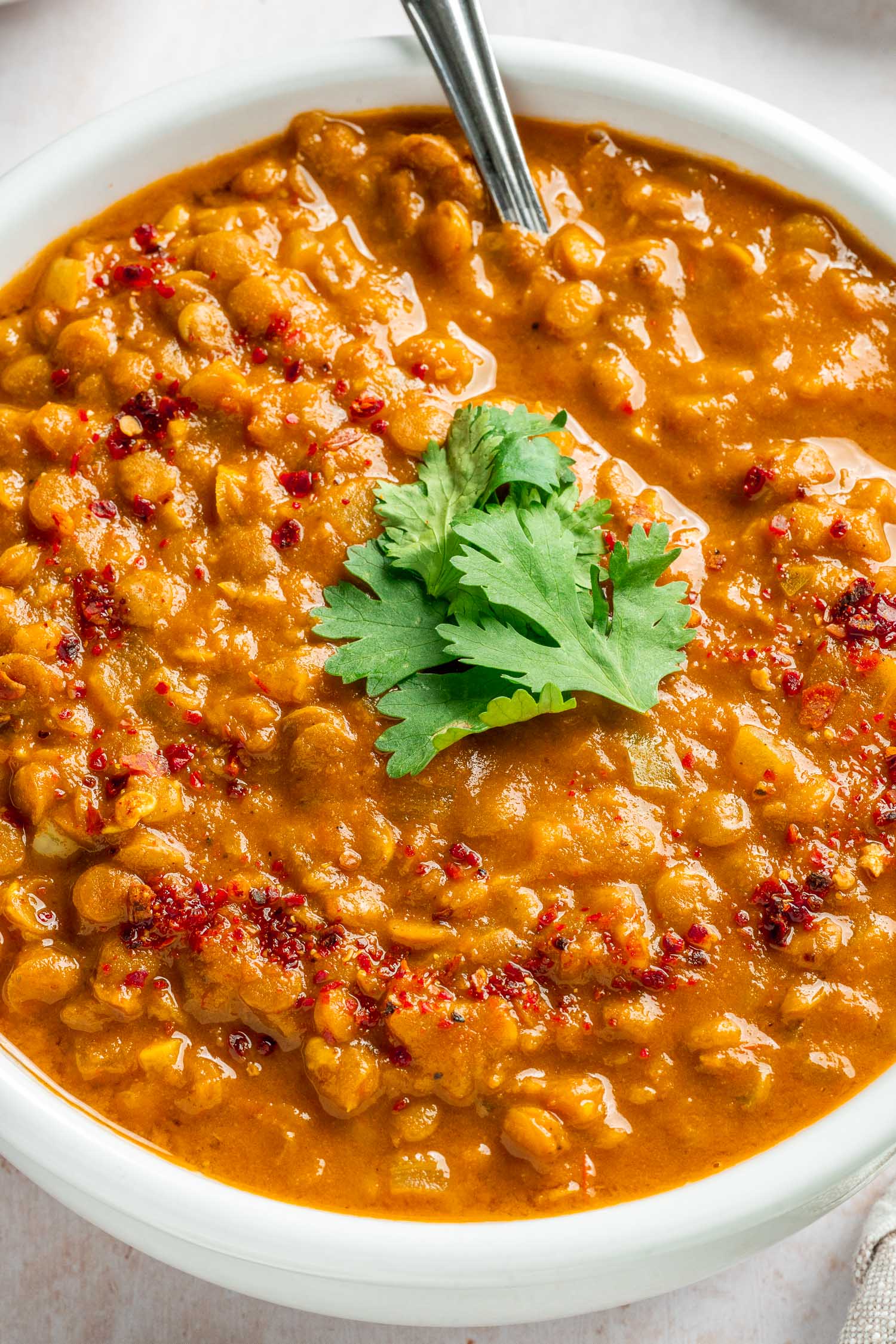 closeup of a bowl of lentil curry with red pepper flakes
